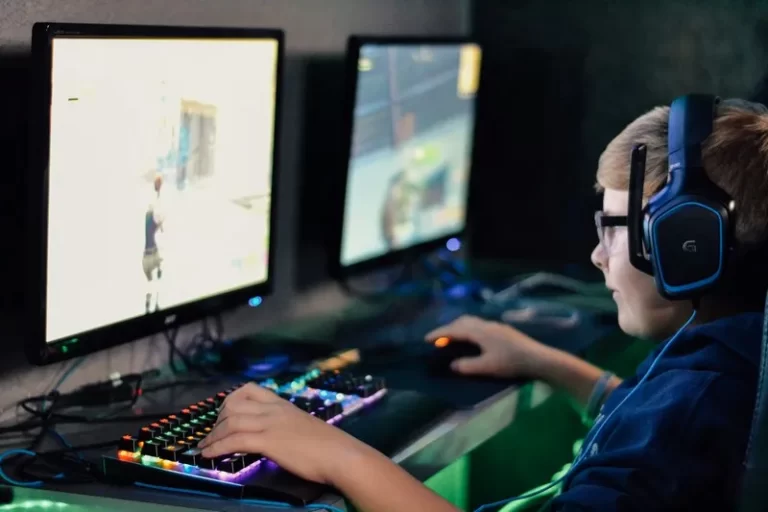 A boy playing video games in the dark wearing headphones