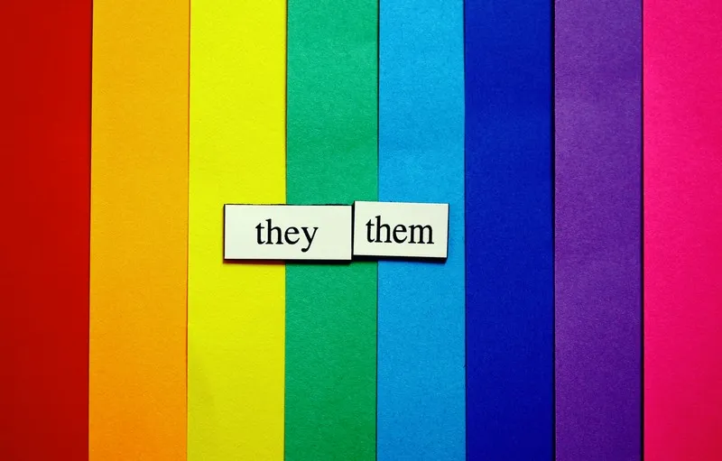 a raindbow background with the words 'they/them'.