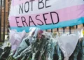A trans movement flag with the words 'we will not be erased'