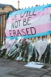 A trans movement flag with the words 'we will not be erased'