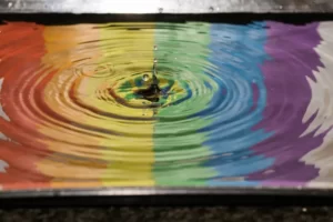 A rainbow image reflected in a rippling puddle