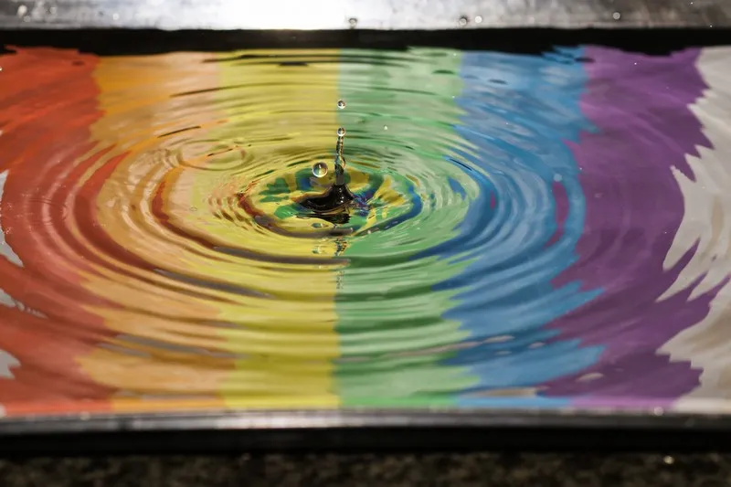 A rainbow image reflected in a rippling puddle