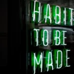 Neon green sign saying 'habits to be made'