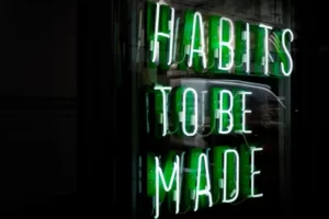 Neon green sign saying 'habits to be made'