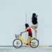 two women riding a bike - one stood on the back wheel - feminism