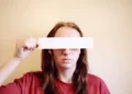 a person holding a white strip across their eyes - identity