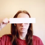 a person holding a white strip across their eyes - identity