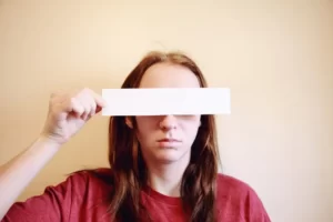 a person holding a white strip across their eyes - identity