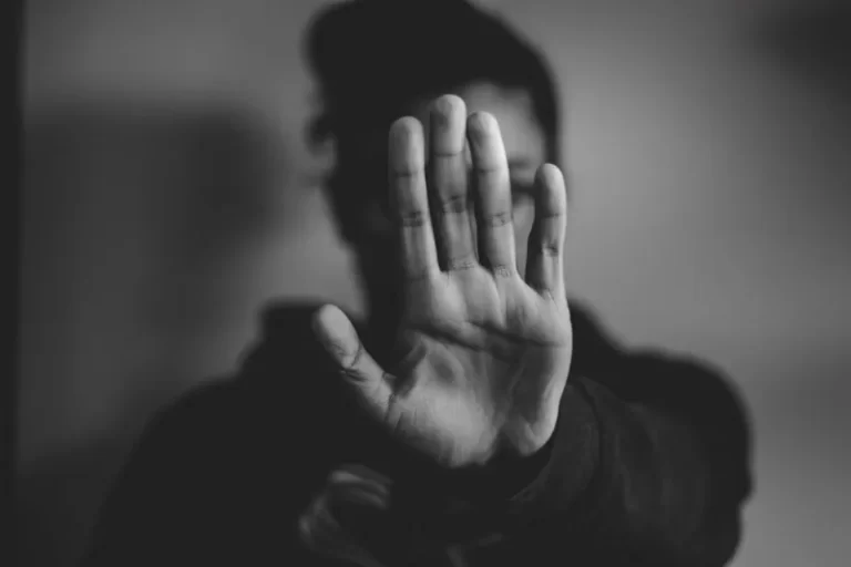black and white image of a person holding their hand in front of their face to symbolise identity oppression