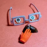 a pair of comedy glasses and various other identity props against a peach background