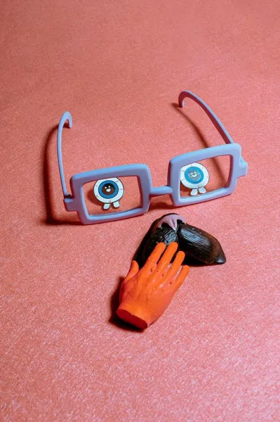 a pair of comedy glasses and various other identity props against a peach background