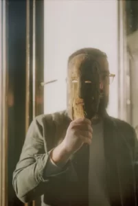 a man holding a wooden mask in front of his face