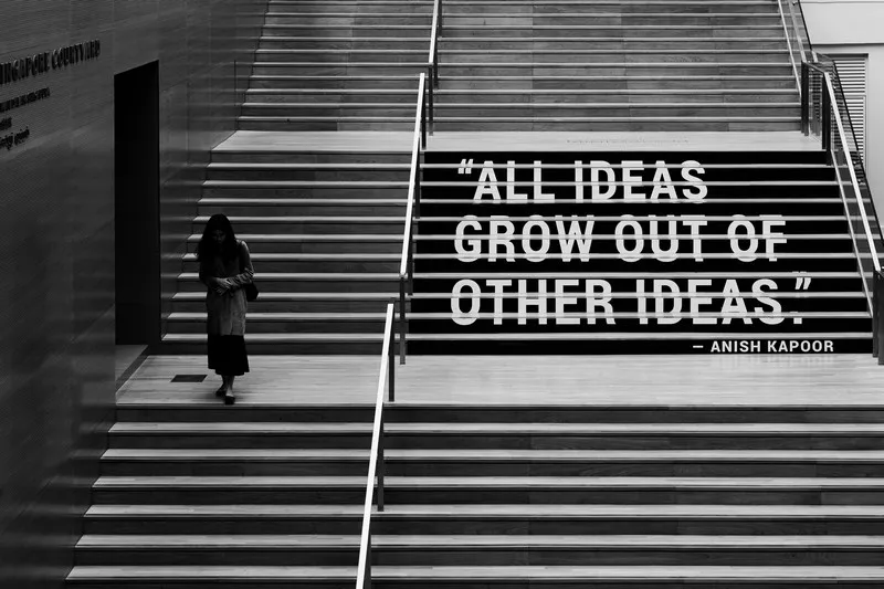 a grey shot of a person climbing stairs with the words 'all ideas grow out of other ideas'