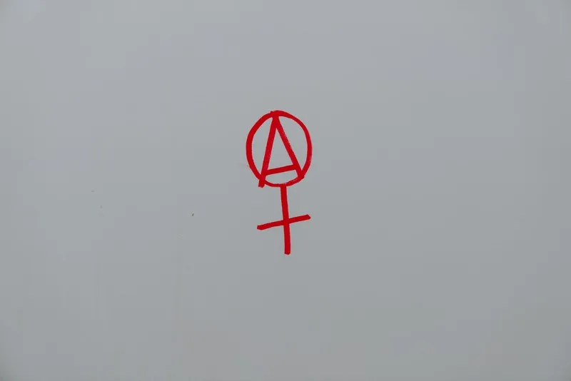an anarchist ideology symbol in red on a white wall