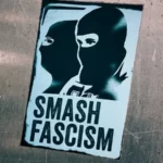 A sign with two people wearing balaclavas with the words 'smash fascism'.