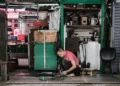 A man in a red tshirt kneeling down on the floor doing work