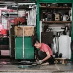A man in a red tshirt kneeling down on the floor doing work