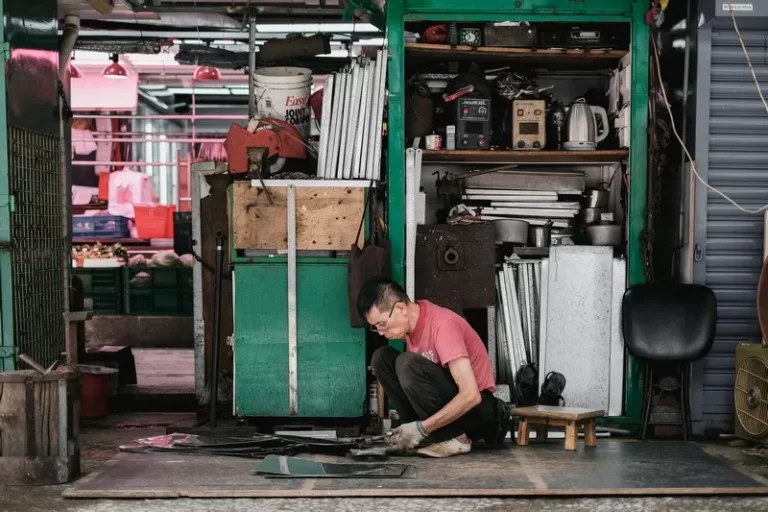 A man in a red tshirt kneeling down on the floor doing work