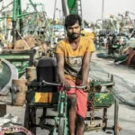An Indian man on a bike in some kind of scrap yard
