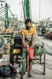 An Indian man on a bike in some kind of scrap yard