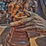 a person with workplace worn hands covered in thick clay