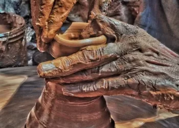 a person with workplace worn hands covered in thick clay