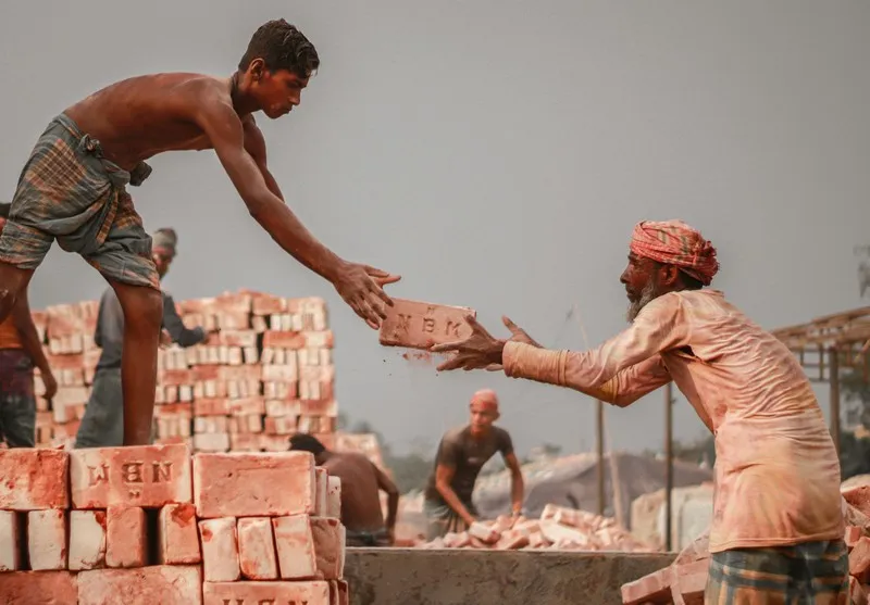 two men passing bricks to each other