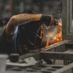 A person welding in a factory as human capital