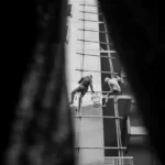 Builders on a giant ladder dangling from the side