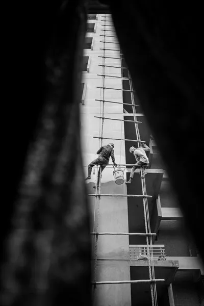 Builders on a giant ladder dangling from the side