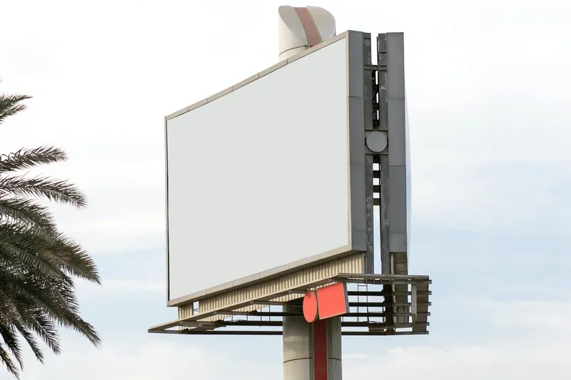 A blank billboard next to a palm tree