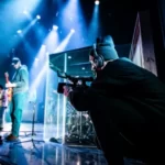 a photographer at a concert kneeling down photographing the band