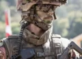 A close up of a soldier wearing sunglasses and carrying a gun