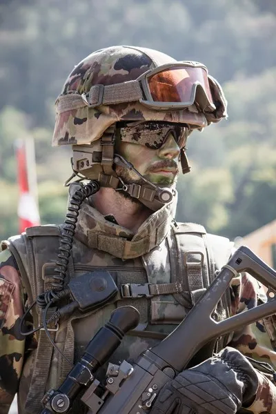 A close up of a soldier wearing sunglasses and carrying a gun