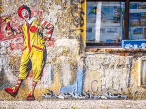 a graffitti image on a wall of ronald mcdonald - capitalism