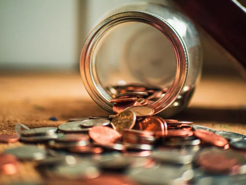 a coin jar tipped over - profit motive education