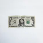 A one dollar bill against a grey background