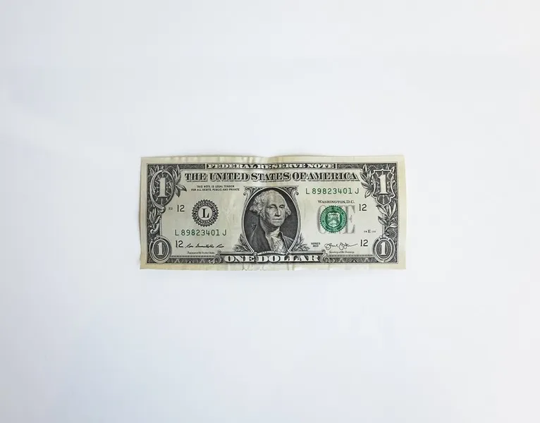 A one dollar bill against a grey background