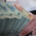 side-facing image of large bundles of cash in various denominations