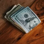 A folded bundle of dollar bills on a brown table