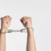 two hands handcuffed against plain background - crime and deviance in functionalism