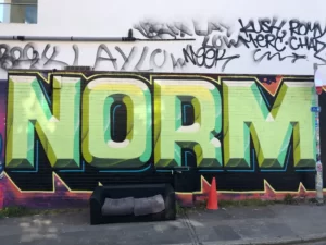 graffiti on a wall saying 'norms'