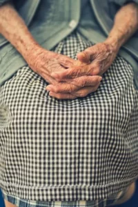 An older person with their hands in their lap
