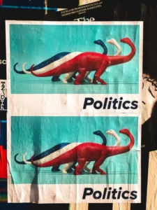 A poster with the word politics and 3 dinosaurs in red white and blue