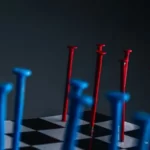 red and blue nails hammered into a chess board