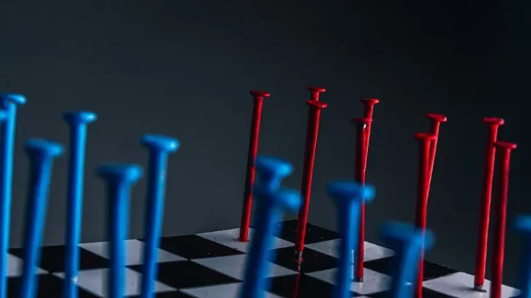 red and blue nails hammered into a chess board