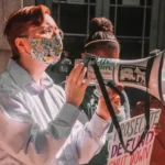 A protester wearing a medical mask carrying a megaphone