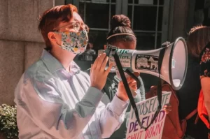 A protester wearing a medical mask carrying a megaphone