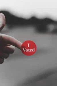 A finger holding a sticker saying 'I Voted'