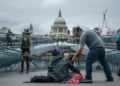 A man giving some change to a homeless man sitting on the floor